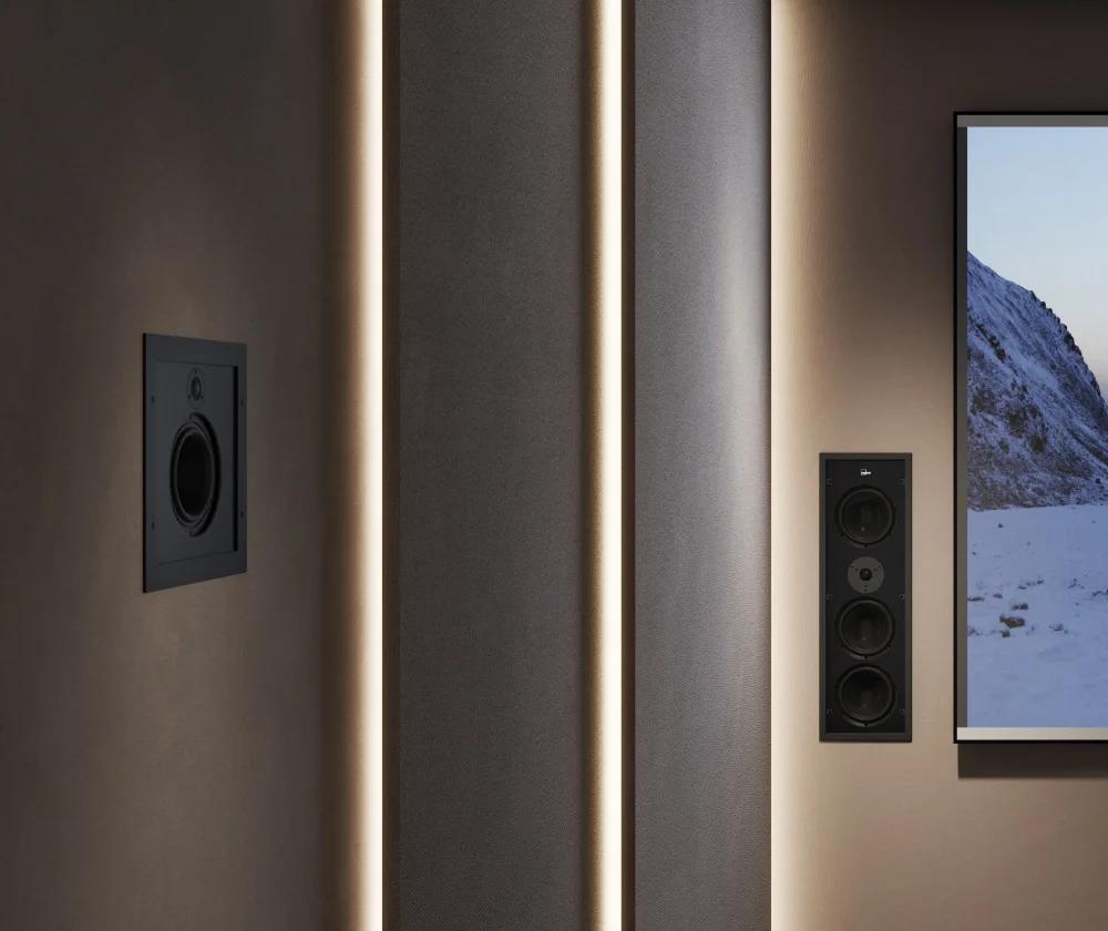 Part of a small cinema auditorium, with Lyngdorf D-500 and D-5 loudspeakers built into the field of view, and a screen showing an image of mountains