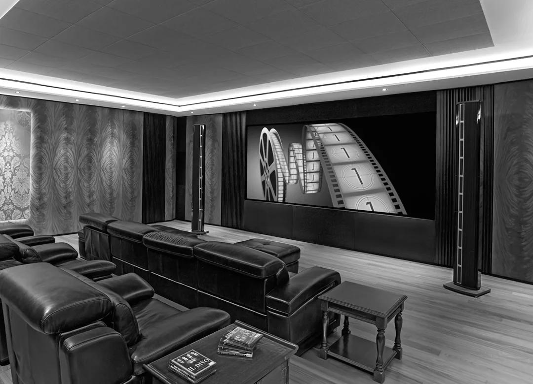 Пара масивів гучномовців Steinway & Sons LS Concert в інтер'єрі великого домашнього кінотеатру в стилі середини 20-го століття, на передньому плані великі зручні крісла