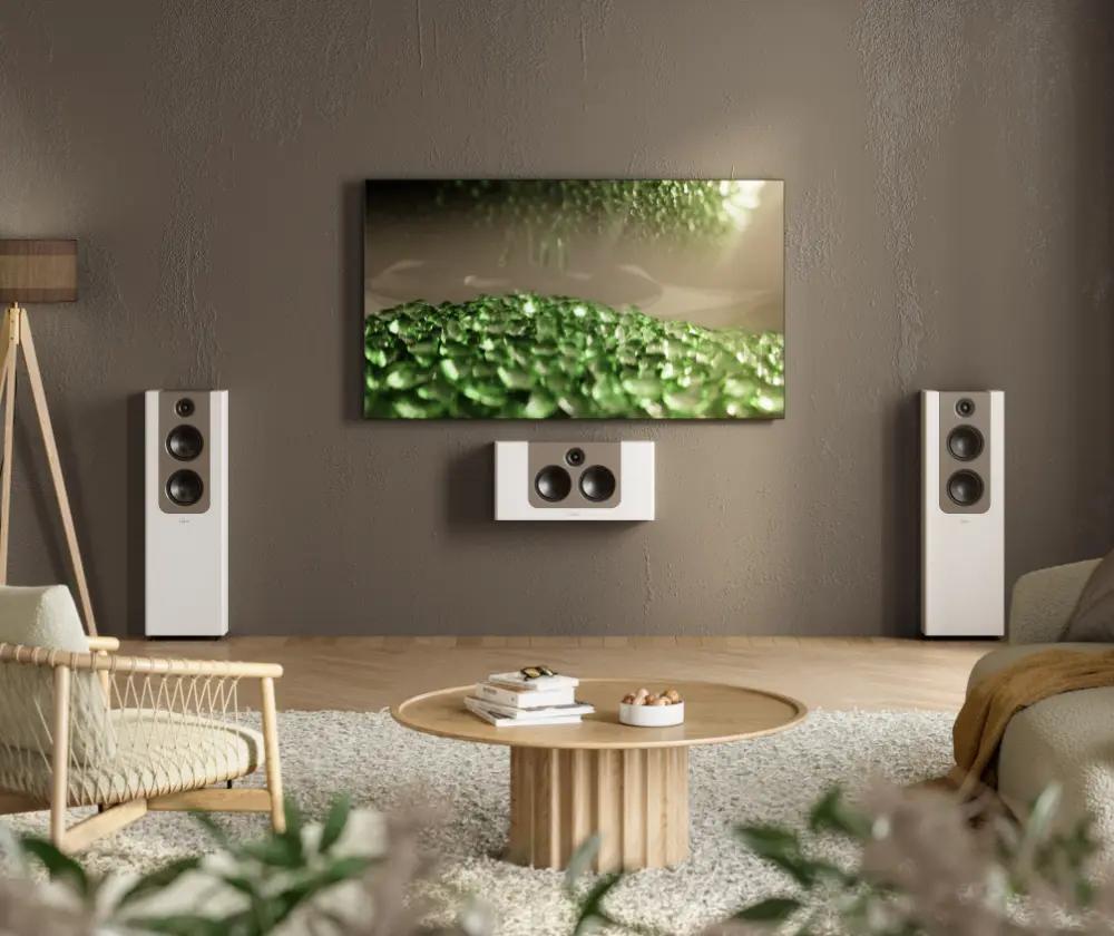 The Lyngdorf FR-2 and LCR-2 speakers are wall-mounted, with white cabinets featuring mocca panels; in the centre is a large television, and the room features a contemporary Scandinavian design