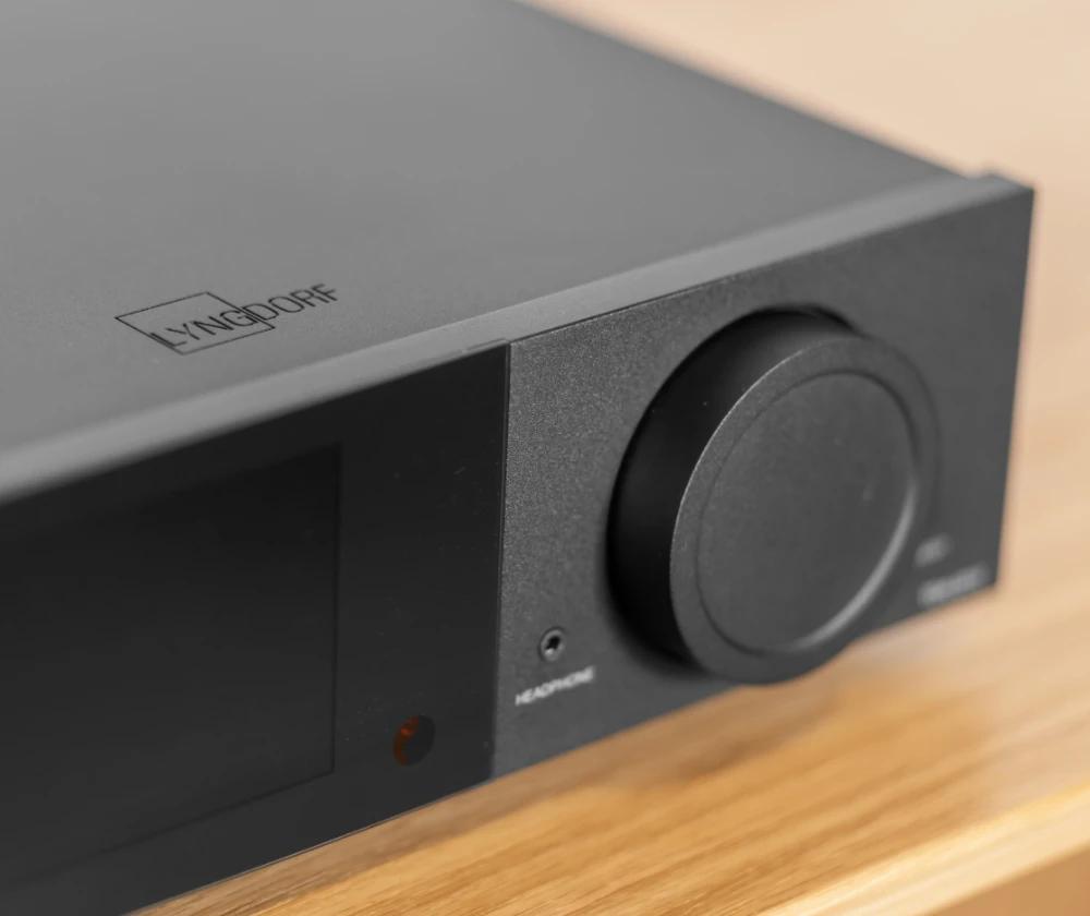 Підсилювач Lyngdorf TDAI-2210, вигляд спереду: великим планом головне колесо регулятора, поруч – гніздо для навушників, зверху на корпусі видно логотип Lyngdorf