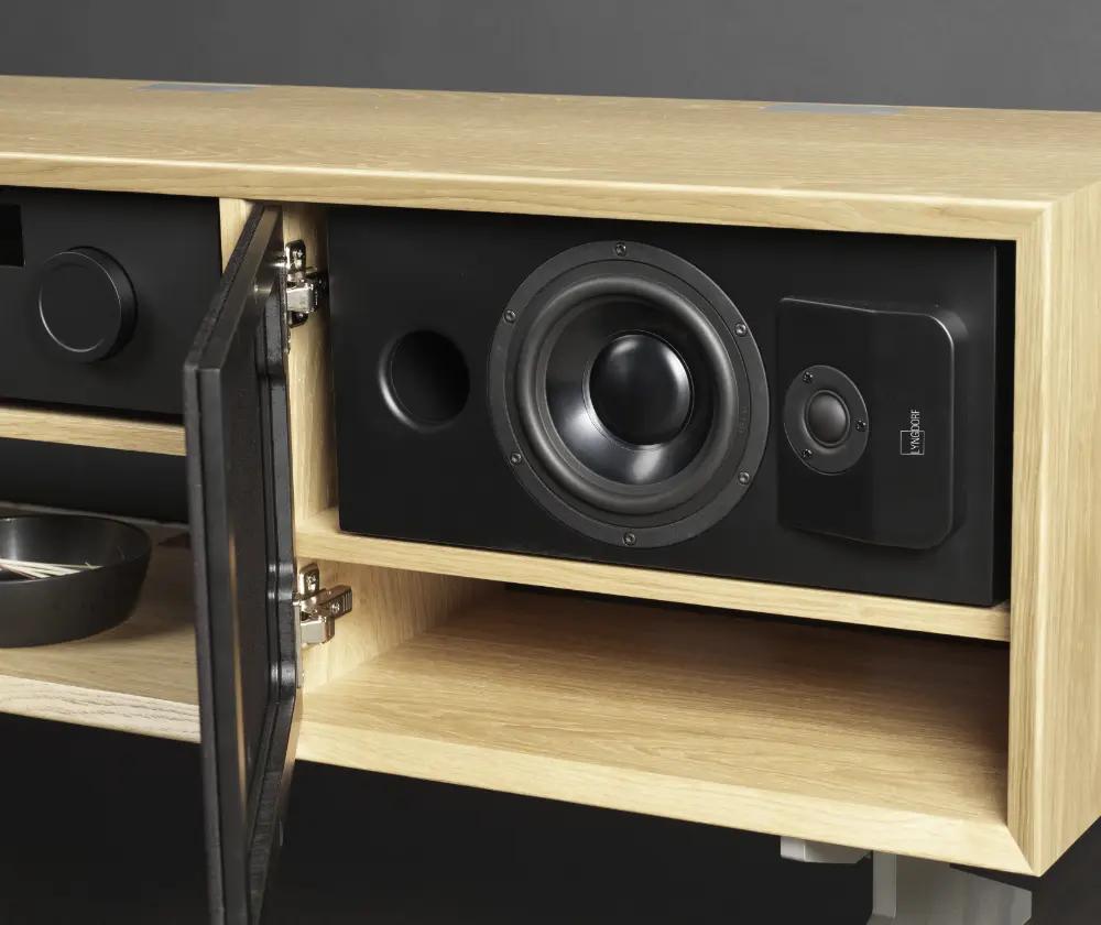 The Lyngdorf CS-1 loudspeaker is placed in a cabinet niche behind acoustically transparent doors (open)