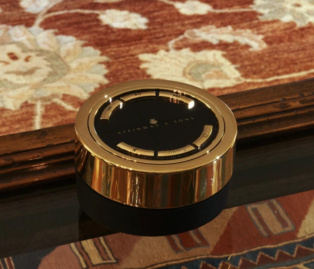  Фірмовий особливий пульт керування Steinway & Sons Remote Control у золотому виконанні, великим планом на столі 
