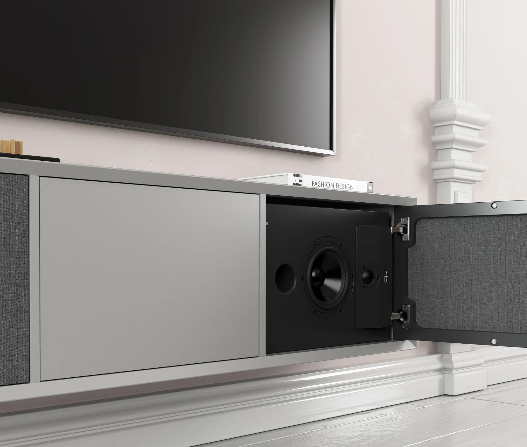 The Lyngdorf CS-2 loudspeaker is placed in a niche in the cabinet behind acoustically transparent doors (open), with a television visible above.
